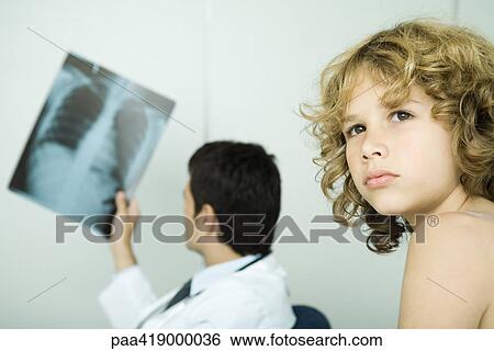 Doctor holding up x-ray while boy looks away View Large Photo Image Stock Photograph - Doctor holding up x-ray while boy looks away. Fotosearch