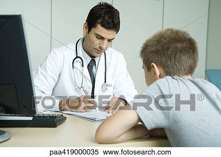 Doctor sitting across from child patient, taking notes View Large Photo Image Stock Photography - Doctor sitting across from child patient, taking notes. Fotosearch