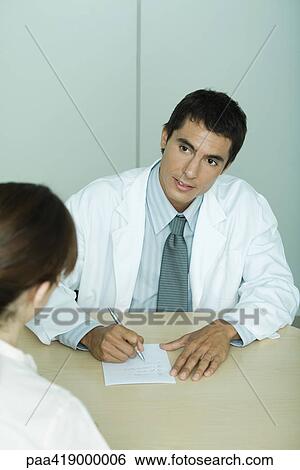 Doctor sitting across from patient, taking notes View Large Photo Image Stock Photograph - Doctor sitting across from patient, taking notes. Fotosearch
