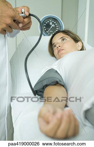 Stock Photograph - Doctor taking woman's blood pressure. Fotosearch