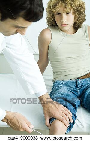 Doctor testing boy's reflexes View Large Photo Image Stock Photo - Doctor testing boy's reflexes. Fotosearch