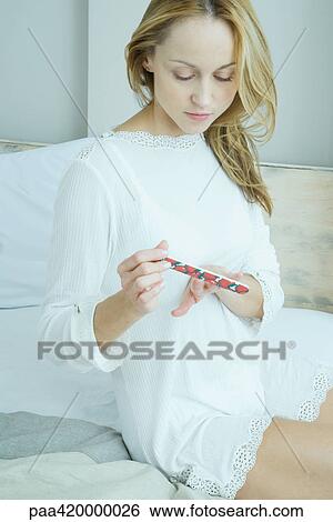 Woman sitting on bed filing nails View Large Photo Image Stock Photograph - Woman sitting on bed filing nails. Fotosearch