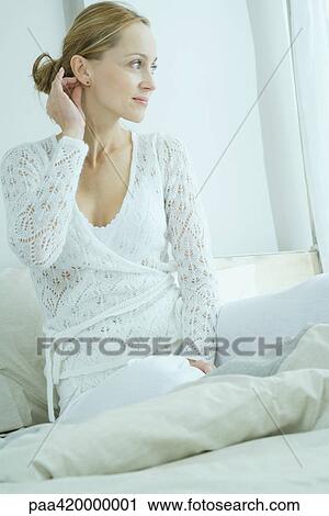 Woman sitting on bed, looking away View Large Photo Image Stock Image - Woman sitting on bed, looking away. Fotosearch
