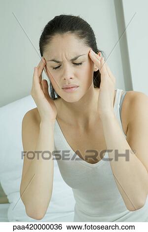 Stock Photograph - Woman touching temples, furrowing brow. Fotosearch