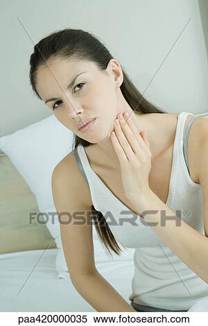 Woman touching throat and furrowing brow View Large Photo Image Stock Photography - Woman touching throat and furrowing brow. Fotosearch