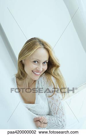 Stock Image - Woman with ponytail holder on fingers, smiling at camera. Fotosearch