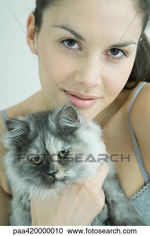 Stock Image - Young woman holding cat, portrait. Fotosearch