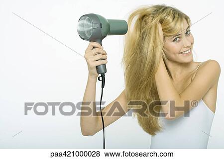 Teenage girl blow-drying hair, smiling at camera View Large Photo Image Stock Photo - Teenage girl blow-drying hair, smiling at camera. Fotosearch