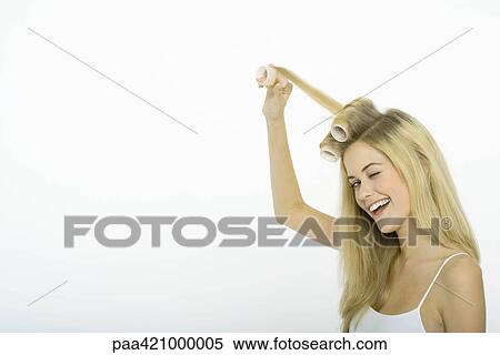 Stock Photography - Teenage girl putting rollers in hair, winking at camera. Fotosearch