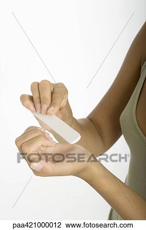 Stock Image - Young woman filing nails, close-up of hands. Fotosearch