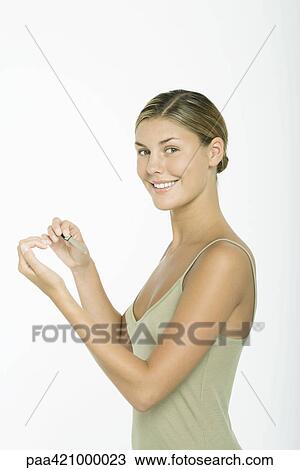 Young woman filing nails, smiling at camera View Large Photo Image Stock Image - Young woman filing nails, smiling at camera. Fotosearch