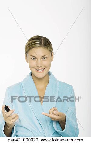 Young woman holding drop of moisturizer on finger, wearing bathrobe, smiling at camera View Large Photo Image Stock Photo - Young woman holding drop of moisturizer on finger, wearing bathrobe, smiling at camera. Fotosearch