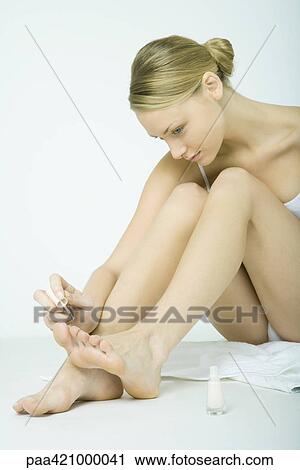 Stock Image - Young woman polishing toenails. Fotosearch