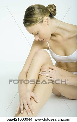 Young woman sitting in underwear, looking at legs View Large Photo Image Picture - Young woman sitting in underwear, looking at legs. Fotosearch