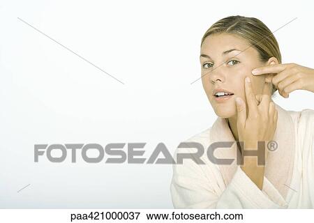 Stock Photo - Young woman touching cheek with fingers. Fotosearch