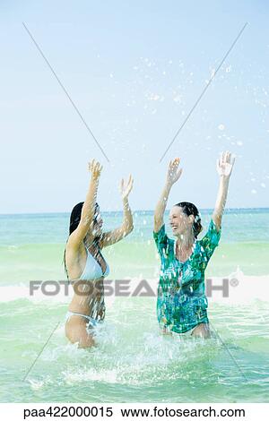 Two young women standing waist deep in sea, splashing View Large Photo Image Stock Photography - Two young women standing waist deep in sea, splashing. Fotosearch