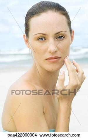 Woman applying sunscreen to face at beach, head and shoulders, portrait View Large Photo Image Picture - Woman applying sunscreen to face at beach, head and shoulders, portrait. Fotosearch
