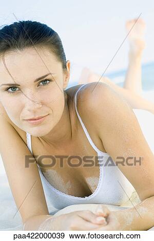 Woman lying on beach, on stomach with legs up, looking at camera View Large Photo Image Stock Photo - Woman lying on beach, on stomach with legs up, looking at camera. Fotosearch