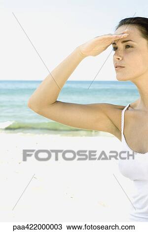 Woman shading eyes, looking away beach in background View Large Photo Image Stock Image - Woman shading eyes, looking away beach in background. Fotosearch