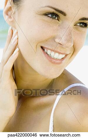 Woman touching cheek, looking away and smiling, close-up, portrait View Large Photo Image Stock Photograph - Woman touching cheek, looking away and smiling, close-up, portrait. Fotosearch