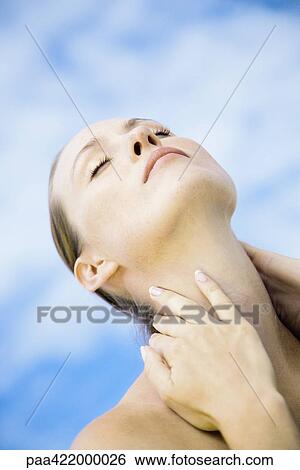 Stock Photograph - Woman with head back and eyes closed, touching neck. Fotosearch