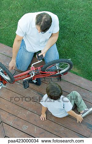 Picture - Father helping son fix bicycle. Fotosearch