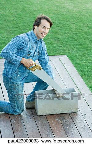 Man sawing piece of wood View Large Photo Image Stock Image - Man sawing piece of wood. Fotosearch