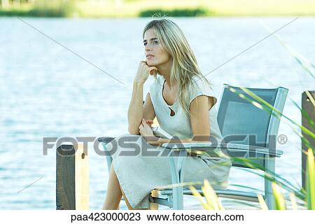 Woman sitting on dock, looking away View Large Photo Image Stock Image - Woman sitting on dock, looking away. Fotosearch