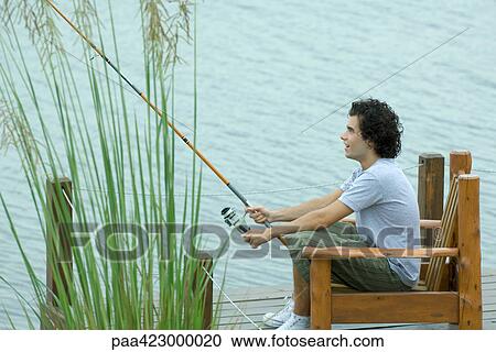 Young man fishing on dock View Large Photo Image Stock Image - Young man fishing on dock. Fotosearch