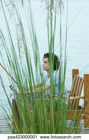 Young man sitting on dock, fishing View Large Photo Image Stock Image - Young man sitting on dock, fishing. Fotosearch