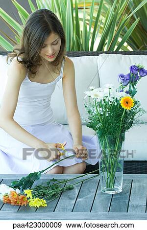 Stock Photo - Young woman making flower arrangement outdoors. Fotosearch