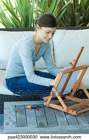 Young woman sitting with easel, drawing with pastels View Large Photo Image Stock Image - Young woman sitting with easel, drawing with pastels. Fotosearch