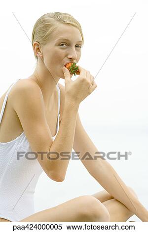 Stock Photography - Teenage girl in bathing suit eating strawberry. Fotosearch