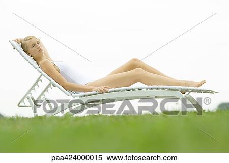 Stock Photography - Teenage girl in swimsuit sitting on lounge chair. Fotosearch