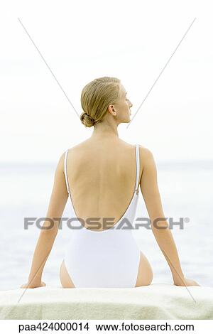 Picture - Teenage girl sitting, wearing bathing suit, rear view. Fotosearch