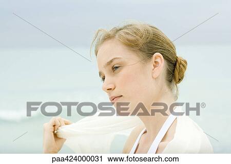 Stock Image - Young woman, head and shoulders, sea in background. Fotosearch