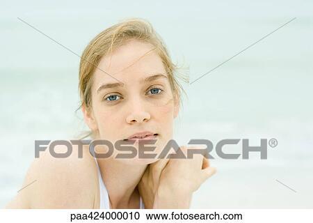 Stock Image - Young woman, head and shoulders, portrait, sea in background. Fotosearch