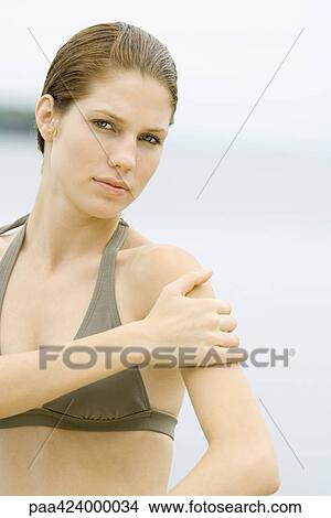 Young woman in bathing suit with hand on shoulder View Large Photo Image Picture - Young woman in bathing suit with hand on shoulder. Fotosearch