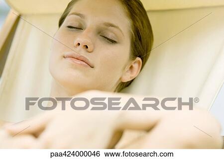 Young woman relaxing in lounge chair, eyes closed View Large Photo Image Stock Photograph - Young woman relaxing in lounge chair, eyes closed. Fotosearch