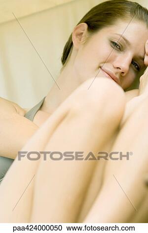 Young woman sitting with knees up, smiling at camera View Large Photo Image Stock Image - Young woman sitting with knees up, smiling at camera. Fotosearch