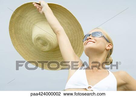 Young woman wearing sunglasses, holding up sunhat, head and shoulders View Large Photo Image Stock Image - Young woman wearing sunglasses, holding up sunhat, head and shoulders. Fotosearch