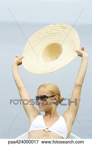 Young woman wearing sunglasses, holding up sunhat, head and shoulders View Large Photo Image Stock Photo - Young woman wearing sunglasses, holding up sunhat, head and shoulders. Fotosearch