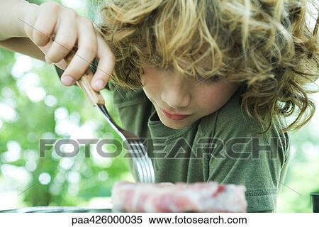 Boy picking up piece of raw meat with fork View Large Photo Image Stock Photography - Boy picking up piece of raw meat with fork. Fotosearch