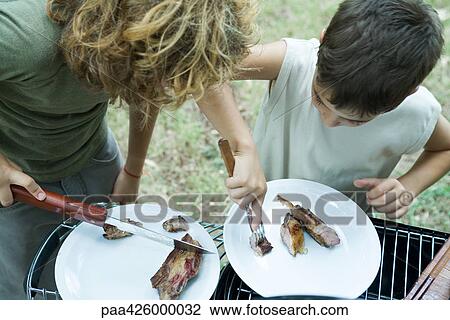 Boys sharing piece of grilled meat View Large Photo Image Stock Image - Boys sharing piece of grilled meat. Fotosearch