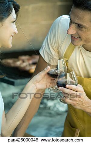 Stock Photograph - Couple having cookout and clinking wine glasses. Fotosearch