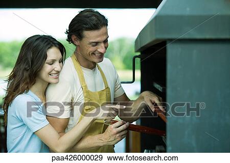 Couple having cookout together, woman pointing to barbecue View Large Photo Image Stock Photo - Couple having cookout together, woman pointing to barbecue. Fotosearch