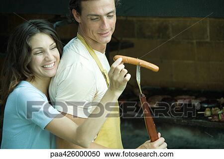 Couple having cookout, woman taking hotdog from man's fork View Large Photo Image Stock Image - Couple having cookout, woman taking hotdog from man's fork. Fotosearch