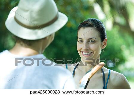 Couple standing face to face outdoors, one holding up hot dog View Large Photo Image Stock Photo - Couple standing face to face outdoors, one holding up hot dog. Fotosearch