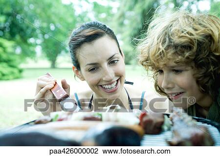 Family having cookout, woman and boy looking at food grilling View Large Photo Image Stock Image - Family having cookout, woman and boy looking at food grilling. Fotosearch