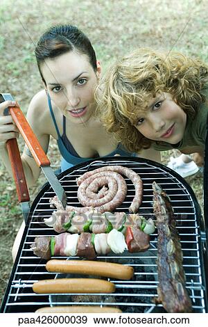 Family having cookout, woman and boy next to barbecue, smiling at camera View Large Photo Image Stock Photo - Family having cookout, woman and boy next to barbecue, smiling at camera. Fotosearch
